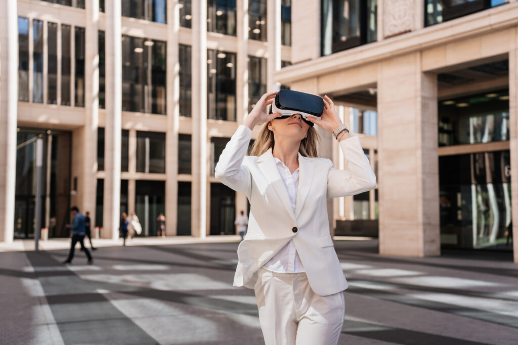 Elegant caucasian woman in white suit using virtual reality glasses in city. Young swedish woman
